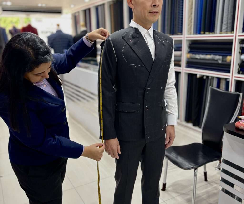 Tailor measuring sleeve length during a pinned jacket fitting