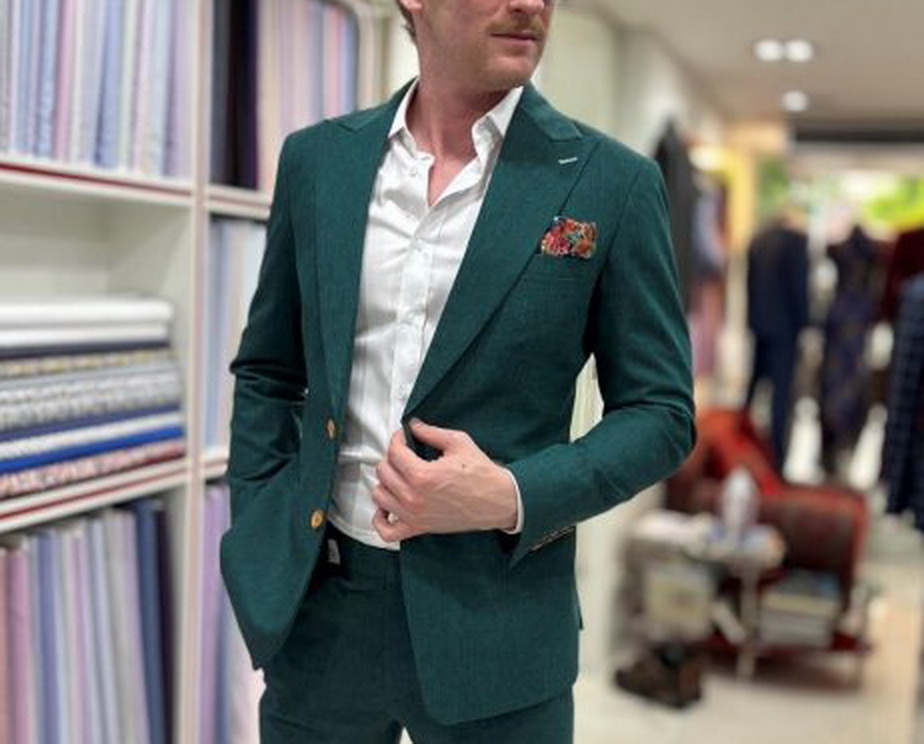 Man adjusting a green suit jacket during a fitting