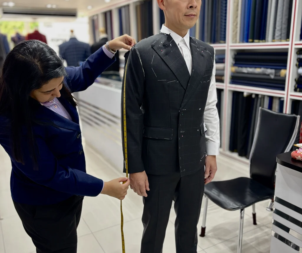 Fitter measuring a customer’s unfinished suit jacket at Jhasper Fashion in Bangkok.