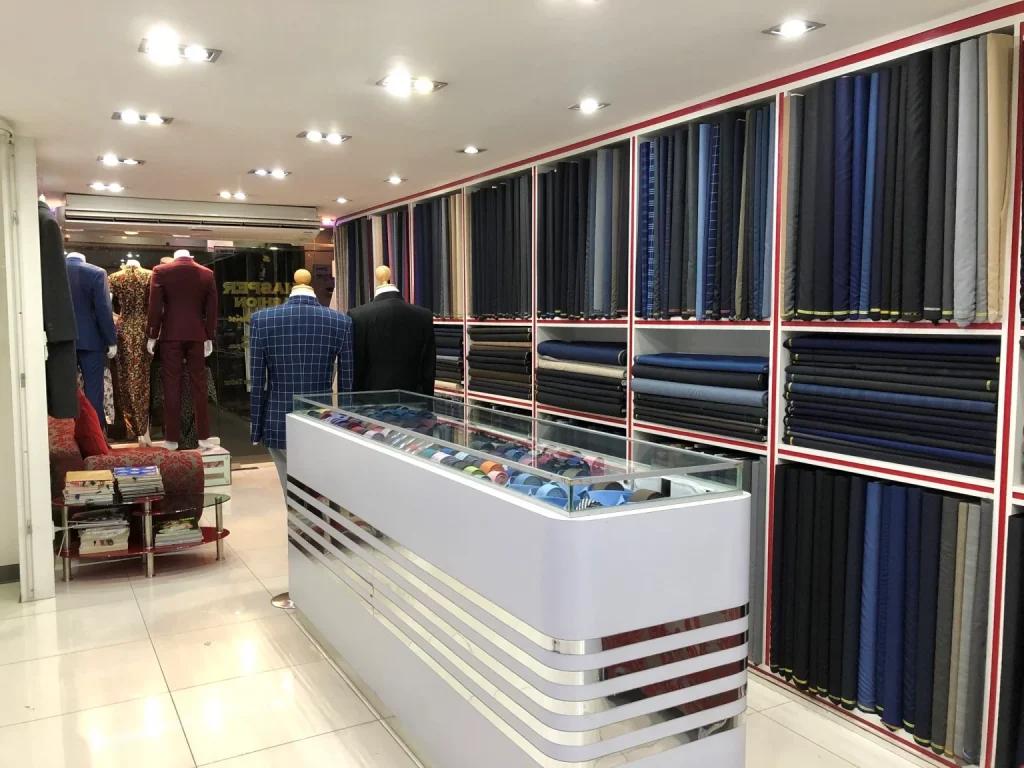 Tailored suits and fabric shelves inside Jhasper Fashion in Bangkok.